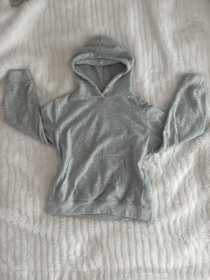 Ljusgrå hoodie med huva - En enkel och stilren ljusgrå hoodie med huva och magficka. Tillverkad i mjukt sweatshirtmaterial som är skönt mot huden. Perfekt för chill dagar eller när du vill ha en avslappnad look. Klassisk passform och ribbade muddar vid ärmar och nederkant. SÅ MYSIGT ❤️🫰🏻