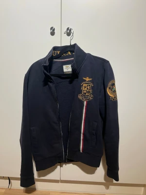 Marinblå zipjacka Aeronautica Militare - Sjukt snygg ziptröja från Aeronautica Militare. Tror jag betalade runt 2500kr för den ny. Den är iprincip som ny. Inga defekter.