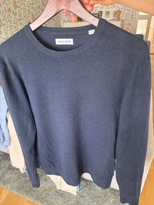 Mörkblå stickad tröja Jack & Jones - Mörkblå stickad tröja från Jack & Jones med rund halsringning och långa ärmar. Enkel och stilren design som passar till det mesta. Perfekt för lager på lager och funkar året runt.