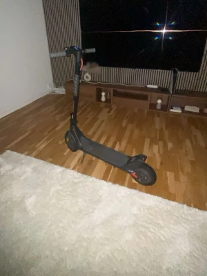 Svart elscooter med röda detaljer - Säljer en svart elscooter med röda detaljer och robust ram. Scootern har bred fotplatta, handtag med greppvänligt material och stora hjul för smidig körning. Perfekt för att ta sig runt i stan eller till skolan. Använd då o då i 3 månader. Den kör 25 kilometer i timmen 