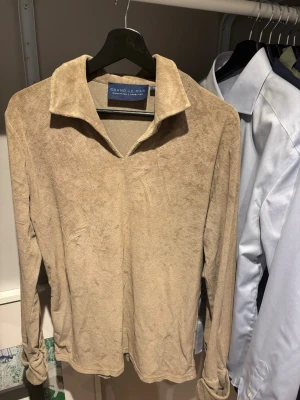 Frotté Long-Sleeve från Grand Le Mar - Olive långärmad tröja från Grand Le Mar i mjukt frotté material. Storlek M. Tröjan har en bred krage och knappar vid ärmsluten för en avslappnad men ändå stilren look. Perfekt för dig som gillar en enkel men snygg stil.