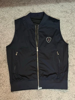 Marinblå L.P Väst - Stilren marinblå väst med enkel och mångsidig design. Perfekt att bära över tröja eller skjorta.  Färg: Marinblå Storlek: XS  Fraktar inom 24h vid snabb affär. Byten är inte aktuella.  #Väst #Marinblå #Streetwear #Menswear #Fashion