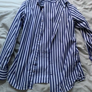 Randig skjorta - Randig skjorta i färgerna blå och vit, perfekt inför sommaren. Köpt från Mango förra sommaren. Skick 9/10 och inga tecken på slitningar finns. Storlek S men passar även M. Pris kan diskuteras, hör av dig vid potentiella frågor!