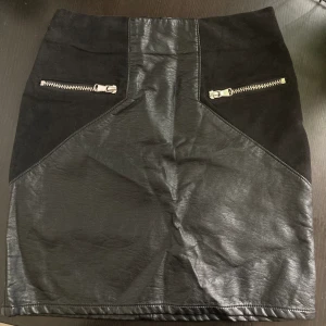 Svart minikjol i fuskläder, 32 XXS, skinn, kjol, mocka, dragkedjor, alternativ -  Svart figurnära minikjol i fuskskinn, dekorativa dragkedjor. Mått får ej plats - fråga gärna!