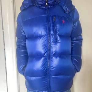 Polo Ralph lauren glossy blue jacket - Blå glossy Ralph lauren jacka, skicket är 9/10 jackan är väldigt skön och varm, inga defekter. Jackan är köpt från Zalando för ca 6000 kr. Skriv för frågor eller fler bilder. PRIS KAN DISKUTERAS VID SNABBT KÖP‼️