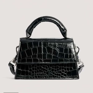 Svart handväska med krokodilpräglat mönster - En elegant svart handväska med krokodilpräglat mönster. Väskan har ett handtag och en avtagbar axelrem med silverfärgade detaljer. Använd endast en gång