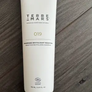 Terre de Mars 019 Revitalizing Shampoo är ett ekologiskt schampo som revitaliserar och återupplivar håret. Förpackningen är vit och innehåller 150 ml.