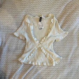 Vit topp med volang - Sååå fin vit topp med volangdetalj. Aldrig använd och lappen är kvar!