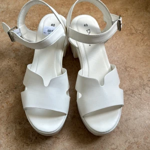 Sandaler med klack - Vita sandaler med klack från Duffy. Endast provade. Storlek 40.  Ordinarie pris 399kr