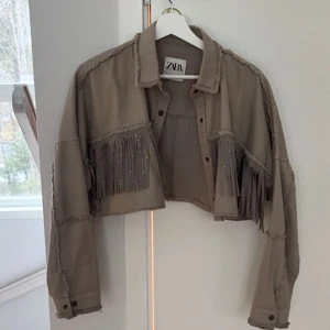 Vårjacka - En croppad jacka med fransar och stenar från zara i storlek S. DIY av mig själv. Mycket bra skick! Använd 1-2 gånger bara. Säljer pga att jag redan har många jackor!