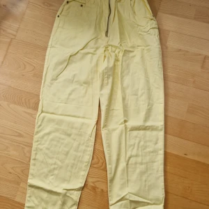 Ljusgula bomullsbyxor - Oanvända ljusgula bomullsbyxor storlek 36. Resår i midjan och fickor både fram och bak.
