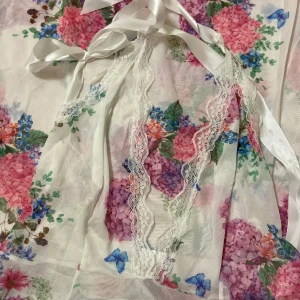 En blommig genomskinlig vårklänning  - En blommig genomskinlig vårklänning med en Knut runt halsen och i slutet av ryggen! 