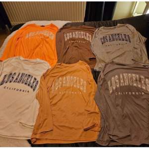 6 st långärmade t shirts/tröjor. orange, vit, aprikosrosa, brun, ljusgrå, mörkgrå. Står los angeles kalifornia på alla, alla är i strl 38. Den orange har en liten fläck vet dock inte om det går bort i tvätten annars fint skick. 