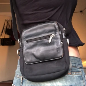 Axelremsväska - En liten svart crossbody väska bra till festivaler elr liknande. Bra kvalitet