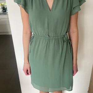 Sommarklänning  - Fin grön klänning med fina detaljer, knytning i midjan och fina volanger på armarna💚aldrig använd, prislapp kvar😊