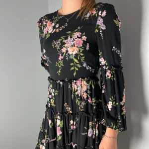 Blommig klänning - Bra skick. ”Öglan” till knappen på baksidan är sönder och därför ihopknuten. Klänningen är i tunt tyg. 