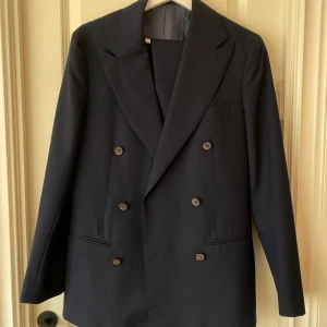 Kostym- SUITSUPPLY - Marinblå kostym i storlek 44, längd på byxa 99cm, hög midja. Ord pris 8000kr, sparsamt använd.