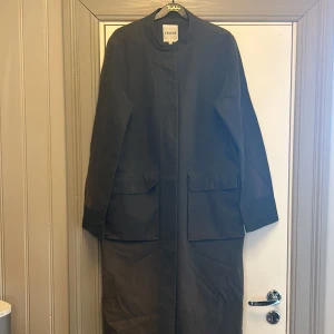 Kappa från Elvine - Grön kappa i linnemix. Dolda knappar. Rejäla fickor med magnetknäppning.  Solblekt på sina ställen, men inget man tänker på när den är på.  Rejäl och dyr i inköp. 