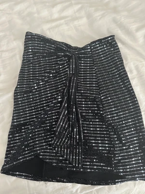 Kjol  - Glittrig kjol  Med slits och knytning 