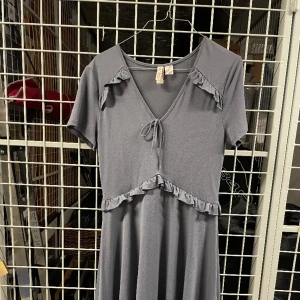 Blå gullig klänning - Dovt blå klänning i stretching och bekvämt tyg. Knappt använd.