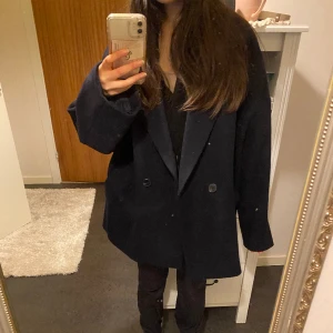 Marinblå ullkappa från Lindex  - Jättefin kappa från Lindex i strl L. Aldrig använd och har prislappen kvar. Jag har vanligtvis strl S och är 165cm och på mig är den oversize, se bilder för referens. 50% ull så bra på att hålla värmen! Köpte för 999kr i höstas men användes aldrig.