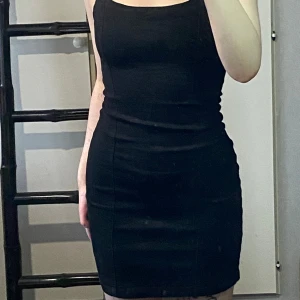 Jeans klänning med textur  - En svart jeans klänning med två ”sträck” på magen, den är väldigt stretchig och stängs med dragkedjan i ryggen, gammal men sällan använd.