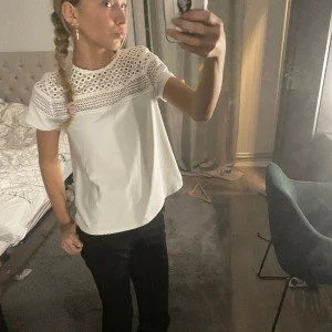 Vit t-shirt med detaljer  - Snygg t-shirt med fina deltaget. Har inte andvänd sen jag köpte den! Det är samma mönster i nacken som där fram. Priset kan diskuteras.
