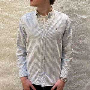 Ralph Lauren skjorta  - Ralph lauren skjorta i färgen blå. Storlek 16 och modellen är 178 cm. Nyskick, inga skavanker. Nypris 1599kr kr, köp för endast 549kr.