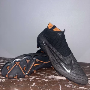 Fotbollsskor ”Nike phantom gx elite Fg black pack” storlek 43 - Skorna är precis som nya och ser bra ut, men dubbarna är lite fula. Skorna är elite vilket betyder att de är de bästa materialen och Verisionen av skorna. Dem kostar 3200kr nya men går inte att få tag på just nu. Bara att skriva vid fler frågor!!  
