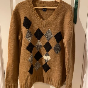 Stickad tröja - Stickad beige tröja med gråa o svarta rutor.