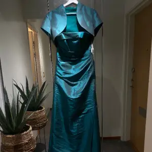 Detta är min mammas grön/turkosa balklänning, endast använd en gång och den har hållits i väldigt bra skick! Det tillkommer en kort kofta samt axelband! Det är storlek M.