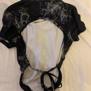 Svart tröja  - Svart tröja öppen bak med snöre och drakar på i vitt använd några gånger 