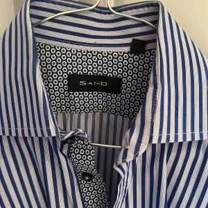Skjorta Sand storlek 38 - Randig skjorta från märket Sand Mycket fint skick, använd enbart enstaka gång! Skjortan tvättad och pressad på kemtvätt inför försäljningen  Storlek 38 regular fit (41cm bred och 73cm lång) 100% bomull