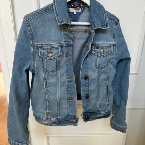 Jeansjacka Tommy Hilfiger nyskick  - Supersnygg jeansjacka från Tommy Hilfiger i nyskick. Väldigt lite använd, tvättad 1 gång inför försäljning. Strl 140. 