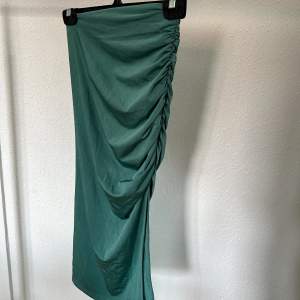 En super vacker grön/blå silkes kjol men ett tjockare tyg som ger en fin form, scrunch och slits på sidan.  Aldrig använd 