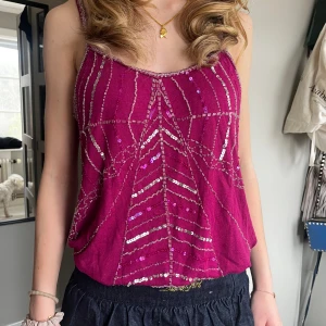 Vinrött linne - Vinrött/mörkt rosa linne med paljetter och fina glitter detaljer. Storlek 42, passar mig som brukar ha XS, det är bara lite långt. Skriv för frågor!