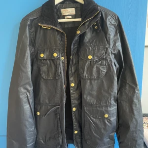 Jacka These Glory Days  - Fin vaxad jacka/kortare oljerock från These Glory Days i storlek S. I använt skick, men har inga skador förutom allmänt bruksslitage. 