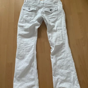 Lågmidjade vintage bootcut jeans med fickor och detaljer - Innerben:76 cm. midja:39 cm. Jag är 167 cm och dom passar mig i längden. Är dock pågränsen t försmå i midjan och därav säljs dom. Älskar dessa med coola fickor från fishbone! Fint skick och bootcut leg. Använd gärna köp nu eller prisförslag🫶