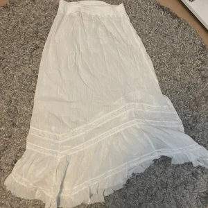 Vit långkjol  - Vit långkjol från Urban outfitters. Knappt använd. Kan vara bra att använda vita underkläder med denna men annars är den hur bra som helst. Är 162 cm lång. 