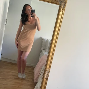 Armlös klänning  - Säljer denna super snygga klänningen från Nelly i sand färg, perfekt för sommaren. Kan användas som kjol! Slits på sidorna❣️