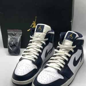 Jordan 1 Mid ’White Metallic Gold Obsidian’ - Storlek 46, väldigt fint skick.