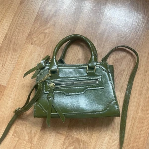 Liten väska  - Säljer denna väska då jag inte använt den, dragkedjan på kanten är en detalj och inte en ficka. 