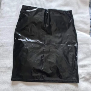 Lack/latex kjol - Kjol i lack/latex från Nelly. Lagom stretchig. Lite osäker på storlek men vid intresse tar jag reda på det!