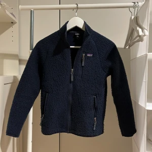 Patagonia fleece - Säljer nu denna riktigt schyssta patagonia jacka/tröja i mörkblå färg. Tröjan är använd, tröjan är lite smått ”nopprig”. Tröjan är även L i barnstorlek, 155-165 (XS/XXS). Nypris: 1250. Slutsåld överallt. Skriv för bilder eller frågor. 