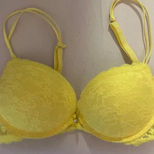 Cool neongul bh. - Köpt på New Yorker. Den är i modellen Super push-up och har en liten krok så att man kan fästa ihop banden till ett X. Fått som present och är endast testad. Den lilla lappen där man ser storleken är bortklippt (vet inte varför). Orginalpris: 199kr 