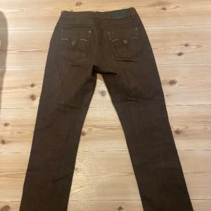 Bruna lågmidjande jeans 💞⚡️ - Bruna ascoola jeans med detaljer där bak som aldrig kommit till användning. Köpta på second hand för nått år sen. Storlek 38 men passar även 36💘