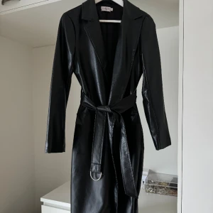 Skinnkappa från NAKD - Snygg oanvänd skinnkappa från NA-KD kollektion tillsammans med ChloeB. Inte riktigt skinn.  Försluts med skärp i midjan.  Storlek 36 men funkar som en 38a likaså då jag själv är det.