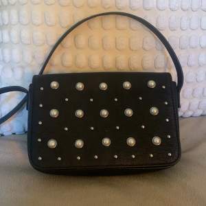 Säljer en svart handväska med silvriga pärlor som dekoration. Använd relativt mycket. Finns en fläck inuti (kolla på bilden) Pris kan diskuteras💗☺️