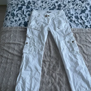  Cargo byxor - Brooker cargo byxor i vit färg. Storleken är 38 och är i perfekt skick förutom att en knapp saknas i baksidan. Skriv vid flera funderingar eller frågor!
