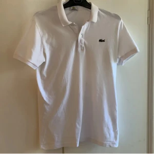 Vit Lacoste piké - En vit Lacoste piké som är perfekt inför sommaren/våren. Piké är i 8/10 kvalitet och har inga tydliga fläckar eller hål. Kontakta mig om du är frågor!!